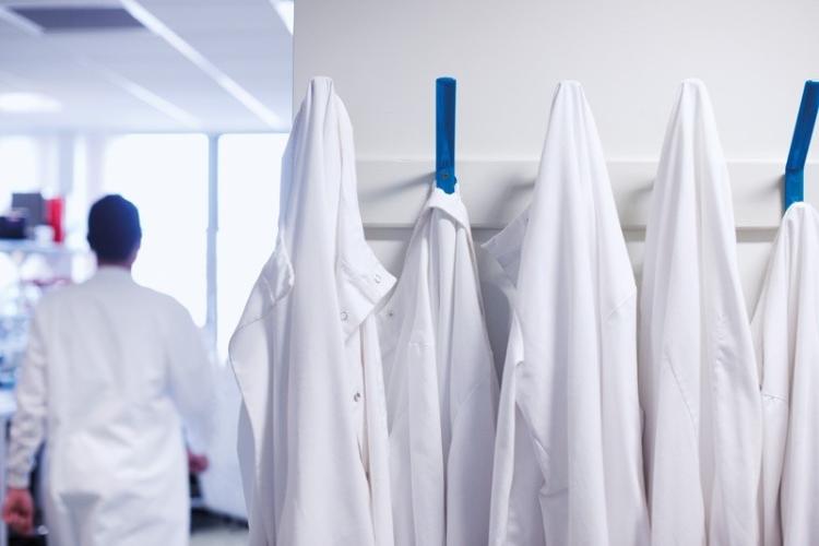 Image of lab coats and a scientist walking away