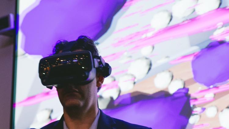 A man wearing a VR headset in front of a colourful background
