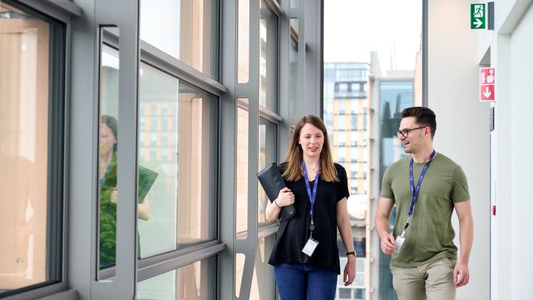 Two people walking down a corridor in discussion