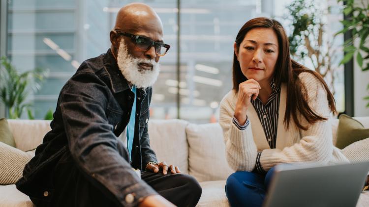A man and a woman sat looking at a laptop