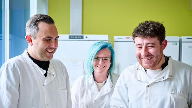 Three people smiling in lab coats