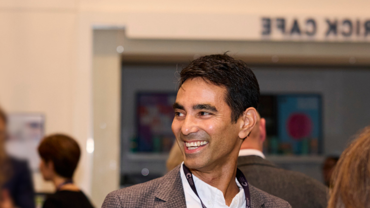 A man smiles at a conference. 