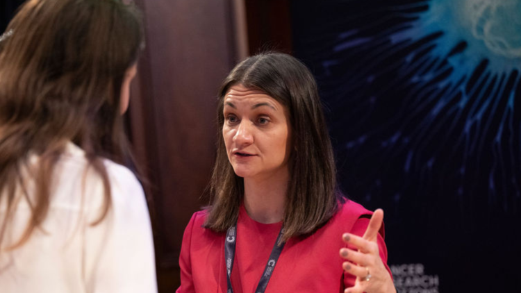 Two people connect at a networking event. One of them wears a white and black top, while the other wears a blue blouse. 