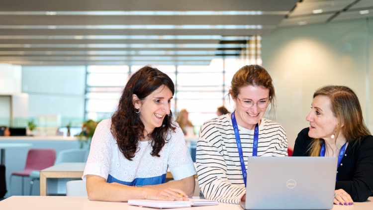 Three women discussing results around a laptop