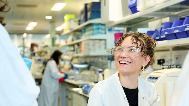 Scientist in a lab smiling and talking to a colleauge