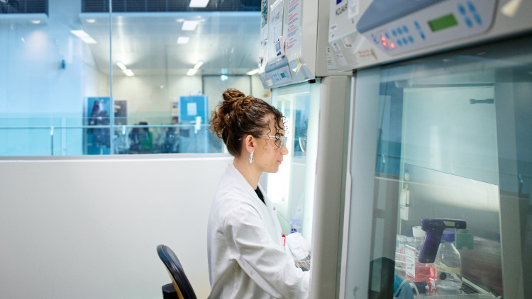 A scientist in a white coat works in a lab. 