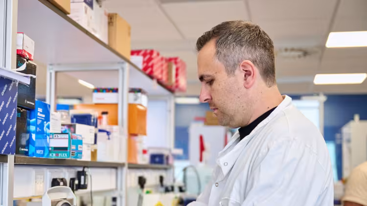 A researcher working in a lab, wearing a white lab coat.