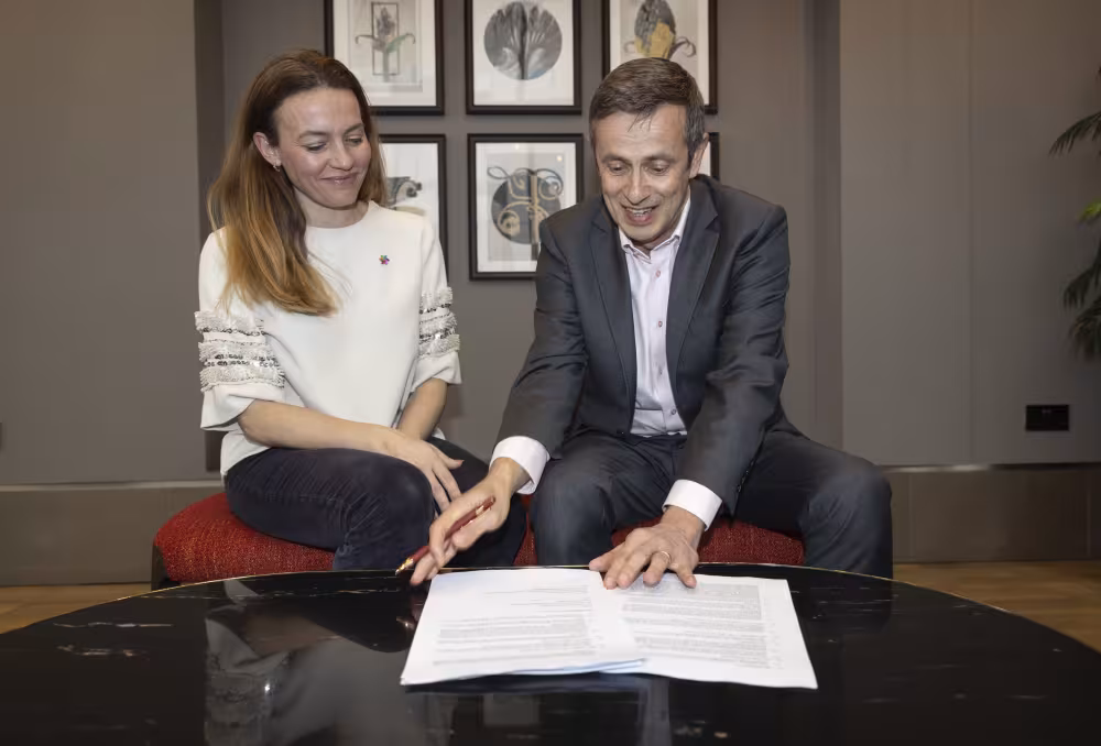 Ingrid Stenstadvold Ross and Lars Erwig smiling while signing the agreement between NCS and CDD