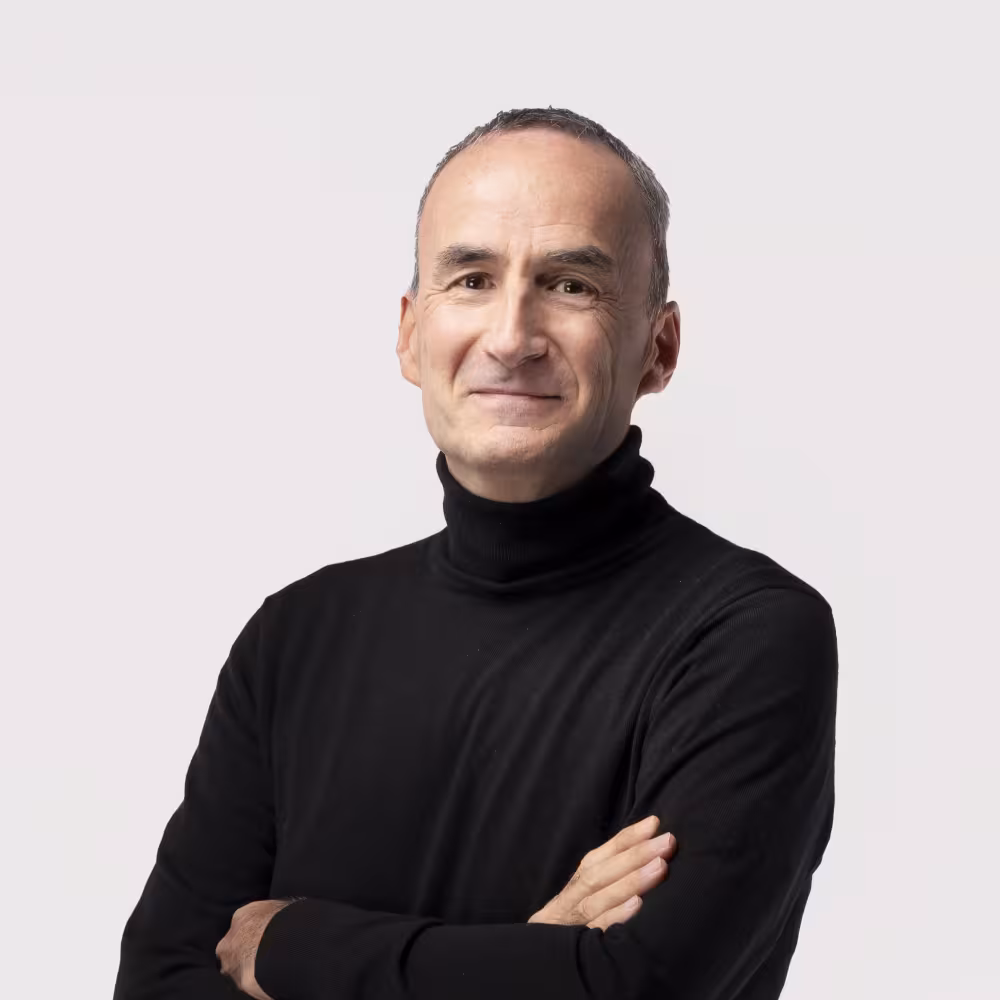A man in a black polo neck with arms folded