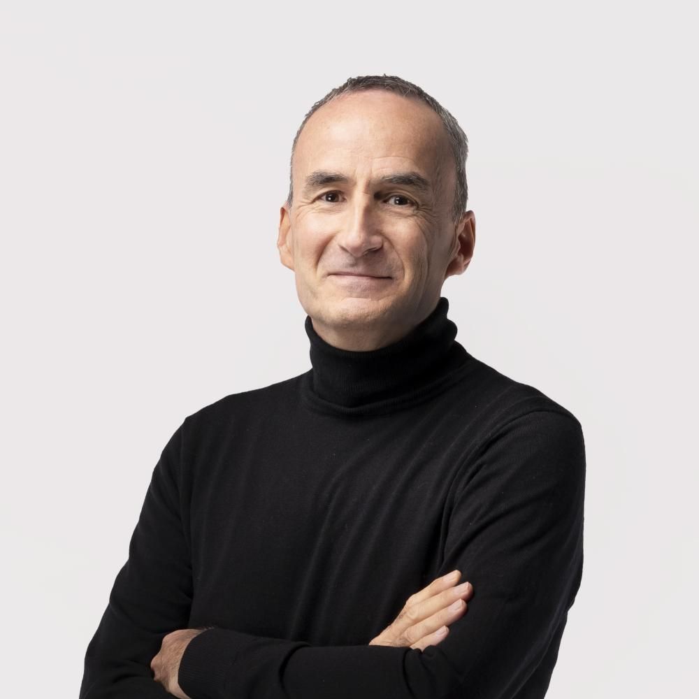 A man in a black polo neck with arms folded