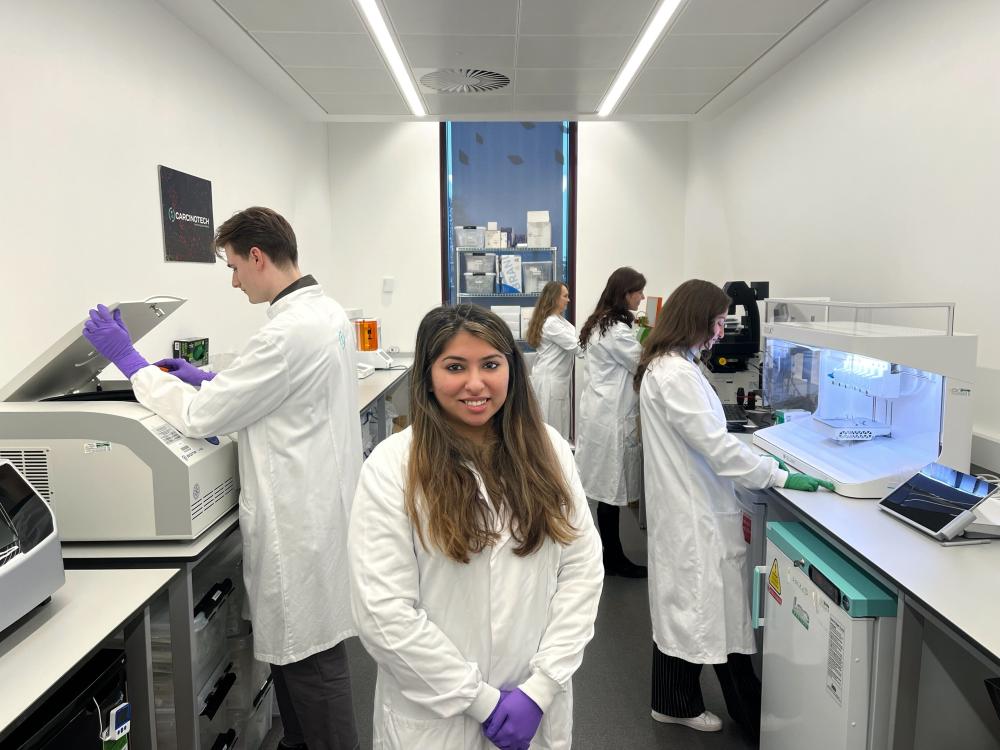 Ishani Malhotra in Carcinotech's lab with four scientists working behind her