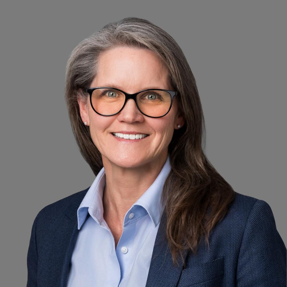 A woman in glasses wearing a shirt and blazer
