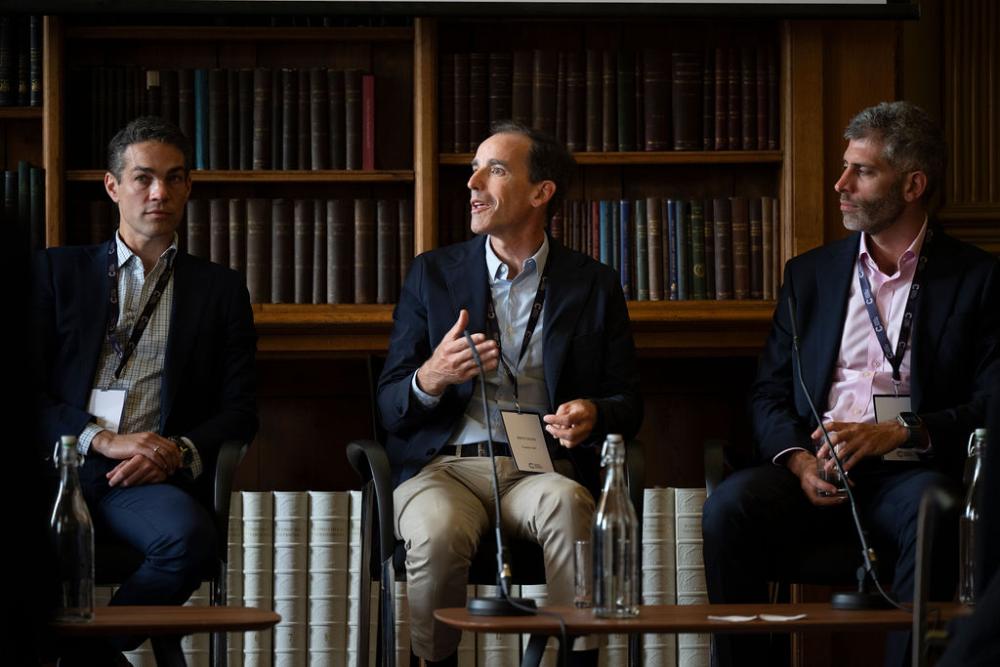 Three panellists speak on a stage